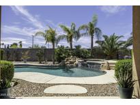 Inviting pool area with rock waterfall, lush landscaping, and a spa for ultimate relaxation at 1123 E Shepherds Way, Casa Grande, AZ 85122