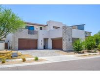 Stunning modern home featuring a stone facade, three-car garage, and desert landscaping at 1221 E Paseo Way, Phoenix, AZ 85042