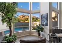 Bright sitting area with large windows overlooking a pool and mountain views, and greenery throughout at 1414 E Cathedral Rock Dr, Phoenix, AZ 85048