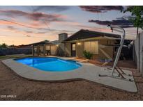 Backyard view of a refreshing pool with a covered patio against a picturesque sunset backdrop at 2009 W Morningside Dr, Phoenix, AZ 85023