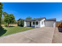 Beautiful home with a well-manicured lawn, mature trees, and a charming white picket fence at 2336 E Flower St, Phoenix, AZ 85016