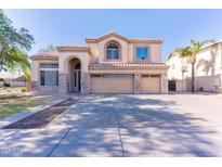 Two-story home with a three-car garage, neutral stucco, stone accents, and a well-manicured front lawn at 2880 E Nunneley Rd, Gilbert, AZ 85296