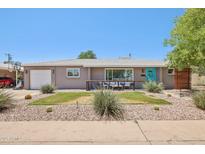 Charming single-story home featuring desert landscaping, a delightful front porch with seating, and a bright blue front door at 5614 N 20Th Dr, Phoenix, AZ 85015