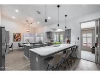 Bright open-concept kitchen with quartz countertops, central island, pendant lights, and stainless steel appliances at 8449 W Rockwood Dr, Peoria, AZ 85382