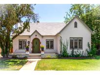 Charming single-story home featuring a white stucco exterior, green door, and lush landscaping at 917 W Willetta St, Phoenix, AZ 85007