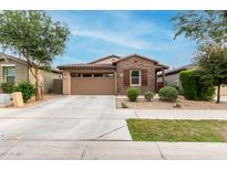 Attractive single-story home featuring brick accents, a two-car garage, and easy-care desert landscaping at 9831 E Tupelo Ave, Mesa, AZ 85212