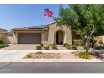 Charming single-story home featuring an arched entryway, desert landscaping, an American flag, and a two car garage at 10310 E Tillman Ave, Mesa, AZ 85212