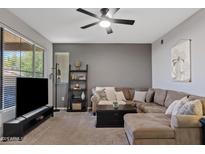 Comfortable living room with a ceiling fan and a large sectional sofa and dark gray accent wall at 11680 E Sahuaro Dr # 2011, Scottsdale, AZ 85259