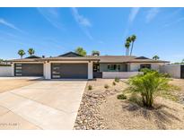 Charming single-story home featuring a three-car garage, modern curb appeal, and a desert-landscaped front yard at 13601 N 50Th Pl, Scottsdale, AZ 85254