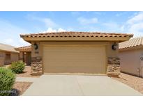Attached two-car garage with neutral door and stone accents, complemented by a tile roof at 23162 W Lasso Ln, Buckeye, AZ 85326