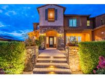 Inviting front entrance featuring stone accents, illuminated steps, and a decorative front door under a classic archway at 27809 N Silverado Ranch Rd, Peoria, AZ 85383