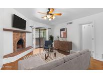 Bright living room features a brick fireplace, ceiling fan, and sliding doors to the outdoor patio at 3031 N Civic Center Plz # 317, Scottsdale, AZ 85251
