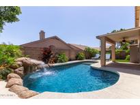 Backyard pool and waterfall feature, surrounded by lush landscaping for a serene retreat at 6787 W Saddlehorn Rd, Peoria, AZ 85383