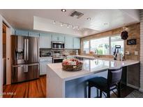 Bright eat-in kitchen with stainless appliances, breakfast bar, and charming modern blue cabinets at 759 W Los Lagos Vista Ave, Mesa, AZ 85210