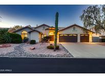 Charming single-story home featuring a three-car garage and mature desert landscaping with a prominent cactus at 12754 E Laurel Ln, Scottsdale, AZ 85259