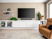 Modern living room features custom built-ins, floating shelves and a mounted television at 13406 W Rowel Rd, Peoria, AZ 85383