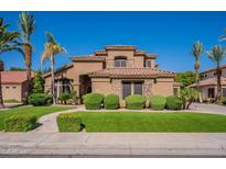 Elegant two-story home featuring a lush lawn, mature palm trees, and attractive desert landscaping at 1808 S Sailors Way, Gilbert, AZ 85295