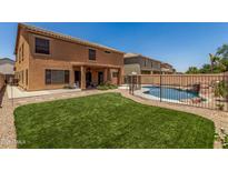 Back of house featuring artificial grass, rock features, and a fenced pool at 18903 N Shelby Dr, Maricopa, AZ 85138