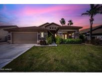 Beautiful home at twilight with lush green grass, desert landscaping, and a two-car garage at 2156 W Periwinkle Way, Chandler, AZ 85248