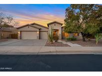 Inviting desert home with a three-car garage and well-maintained front yard under a colorful sunset sky at 2472 E Prescott Pl, Chandler, AZ 85249