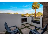 Relaxing outdoor patio features a modern fireplace, stylish seating, and travertine pavers with artificial turf at 3626 N Mohave Way, Scottsdale, AZ 85251