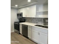 Close up of remodeled kitchen features stainless appliances, white cabinetry, and quartz countertops at 540 E Royal Palms Dr, Mesa, AZ 85203