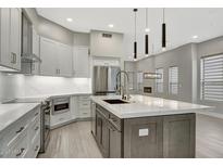 Modern kitchen with gray cabinets, a large island, stainless steel appliances, and stylish pendant lighting at 7525 E Gainey Ranch Rd # 118, Scottsdale, AZ 85258