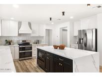 Bright kitchen featuring an island with a waterfall countertop, stainless steel appliances, and white cabinets at 2353 N 51St Pl, Phoenix, AZ 85008