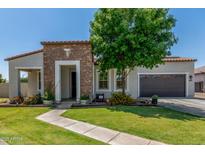 Charming single-story home featuring a stone facade, well-manicured lawn, and mature landscaping at 24350 S 208Th Pl, Queen Creek, AZ 85142