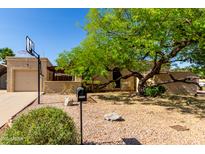 Charming home featuring a basketball hoop, garage, desert landscaping, and a mature shade tree at 4102 W Bluefield Ave, Glendale, AZ 85308
