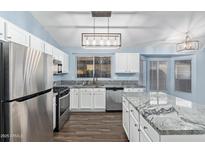 Modern kitchen featuring stainless steel appliances, white cabinets, granite countertops, and a kitchen island at 4911 E Holmes Ave, Mesa, AZ 85206
