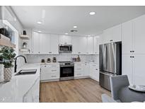 Bright kitchen features white cabinets, stainless steel appliances, marble countertops, and wood-style flooring at 640 S 34Th St, Mesa, AZ 85204