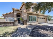 A lush front yard, stone retaining wall, brick walkway, and gated entrance greet you at this two-story home at 1311 N Congress Dr, Chandler, AZ 85226