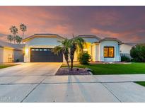 Beautiful one story home with a well-manicured lawn, two palm trees and a two car garage at sunset at 1312 W Bartlett Way, Chandler, AZ 85248