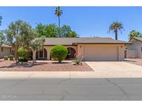 Charming single-story home featuring a well-manicured lawn, mature trees, and a spacious two-car garage at 1953 E Laguna Dr, Tempe, AZ 85282