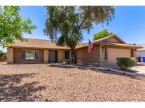 Charming single-story home with a well-maintained desert landscaped front yard and an American flag at 2031 W Gila Ln, Chandler, AZ 85224