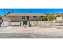 The property's entrance features a secure black metal fence and xeriscape yard, ensuring safety and low maintenance at 3822 W Flower St, Phoenix, AZ 85019