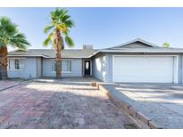 Charming single-story home with gray exterior, a palm tree, and a brick driveway at 4628 W Solano S Dr, Glendale, AZ 85301