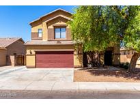 Two-story home featuring a front yard with mature trees and a red two-car garage door at 6320 S 26Th Dr, Phoenix, AZ 85041