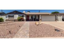 Charming single-story home featuring rock landscaping and a brick walkway to the inviting red front door at 6838 E Belleview St, Scottsdale, AZ 85257