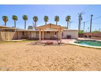 Expansive backyard featuring a refreshing pool, covered patio, and lush palm trees at 809 N Gilbert Ave, Casa Grande, AZ 85122
