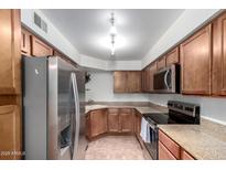Well-lit kitchen featuring stainless steel appliances, stone countertops, and light brown wooden cabinets at 8787 E Mountain View Rd # 1087, Scottsdale, AZ 85258