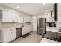 Bright kitchen with white cabinets, stainless steel appliances, and stylish backsplash at 10702 W Salem Dr, Sun City, AZ 85351