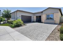 Charming single-story home featuring desert landscaping, a dark garage door, and a spacious paved driveway at 17183 W San Marcos St, Surprise, AZ 85388
