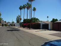 Charming house with flowering bushes and palm trees creating curb appeal and desert charm at 2068 E Cairo Dr, Tempe, AZ 85282