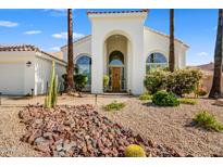 Inviting home featuring a beautiful front yard, mature palms, and an arched entry at 11993 E Mission Ln, Scottsdale, AZ 85259