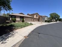 Street-level view of desert home with attached garages, beige stucco and tile roof at 12938 W Alvarado Rd, Avondale, AZ 85392