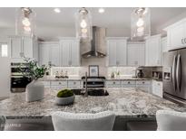 A close-up of the kitchen island featuring granite countertop, stainless appliances, and pendant lighting at 16373 W Beautiful Ln, Goodyear, AZ 85338