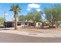 Charming single story home featuring desert landscaping, mature trees, and a red front door at 1749 W Monterosa St, Phoenix, AZ 85015