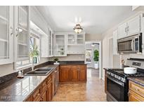 Traditional kitchen featuring glass front cabinets, stainless appliances, and a sink with a window view at 1749 W Monterosa St, Phoenix, AZ 85015